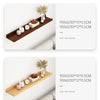 A natural wood floating shelf displaying a ceramic teapot, clocks, and dried floral arrangement on a white wall.