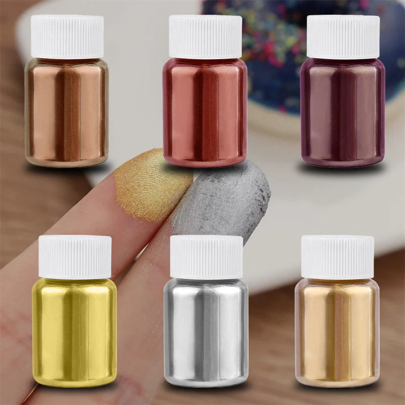 A collection of glass vials containing gold, silver, and rose-colored glitter dust for baking.