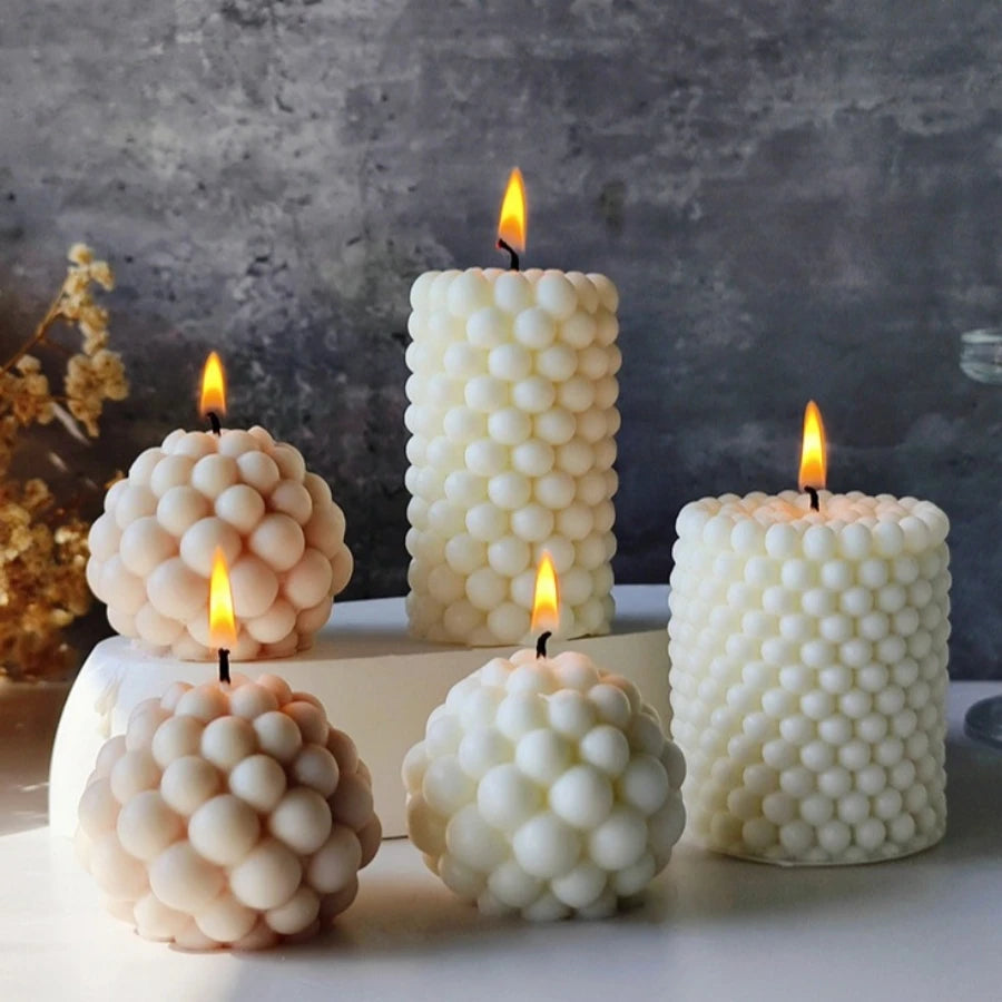A collection of white and cream Nordic bubble scented soy candles are displayed on a light surface against a gray background.