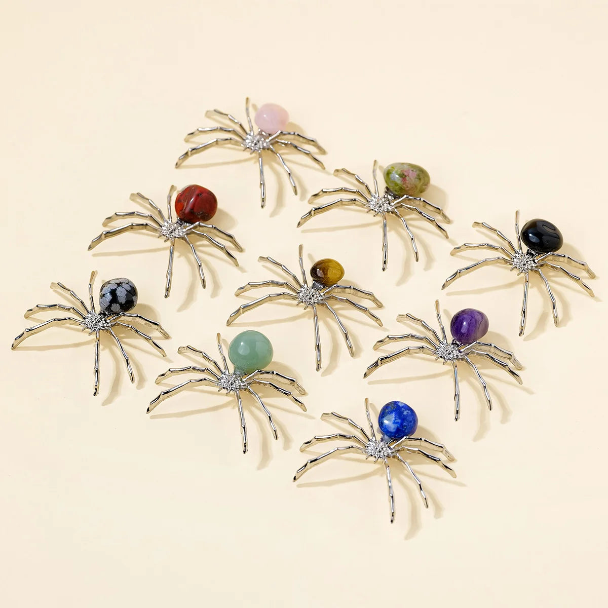 A collection of handcrafted crystal spider figurines in various gemstone colors, arranged on a light background.