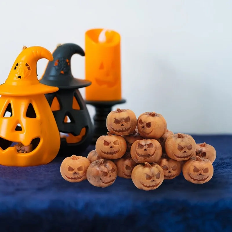 A collection of small, carved resin pumpkins in various shades of orange and brown displayed next to a lit candle.