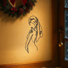 A black line art silhouette of a girl's face and hair is displayed on a wall above a window with a festive wreath.