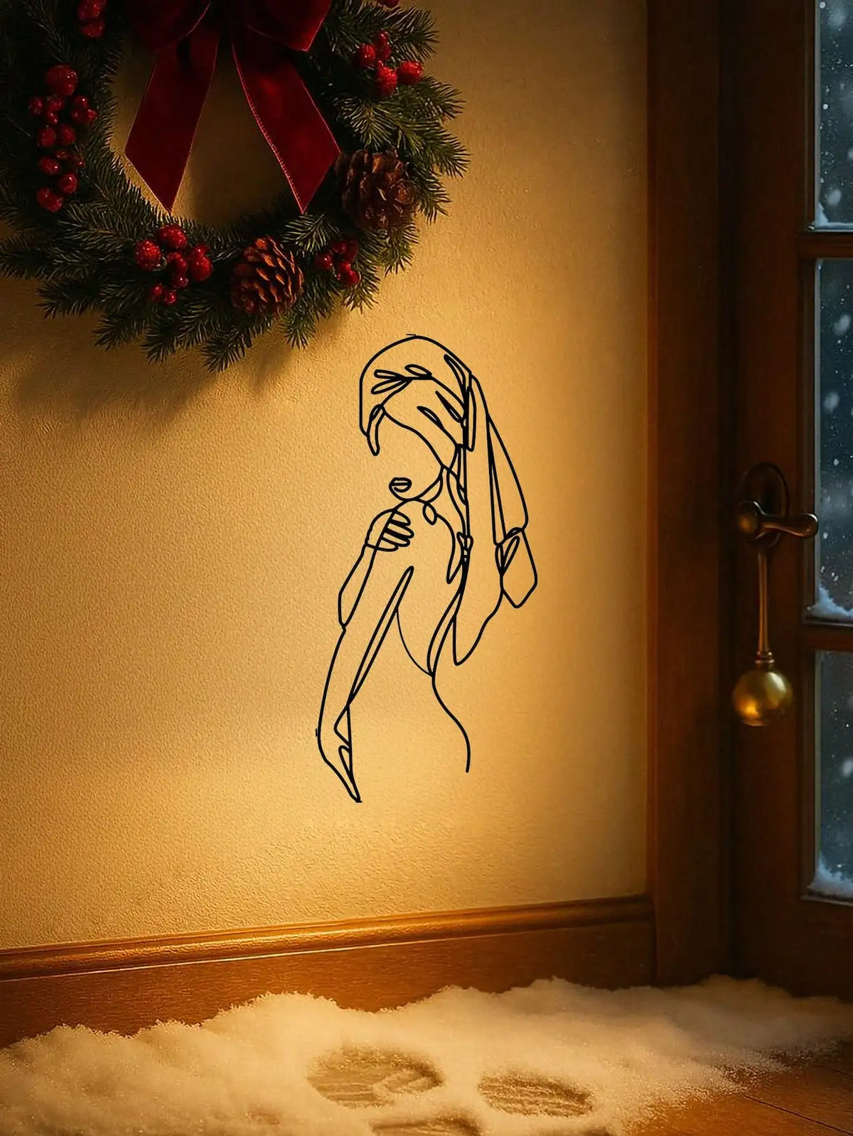 A black line art silhouette of a girl's face and hair is displayed on a wall above a window with a festive wreath.