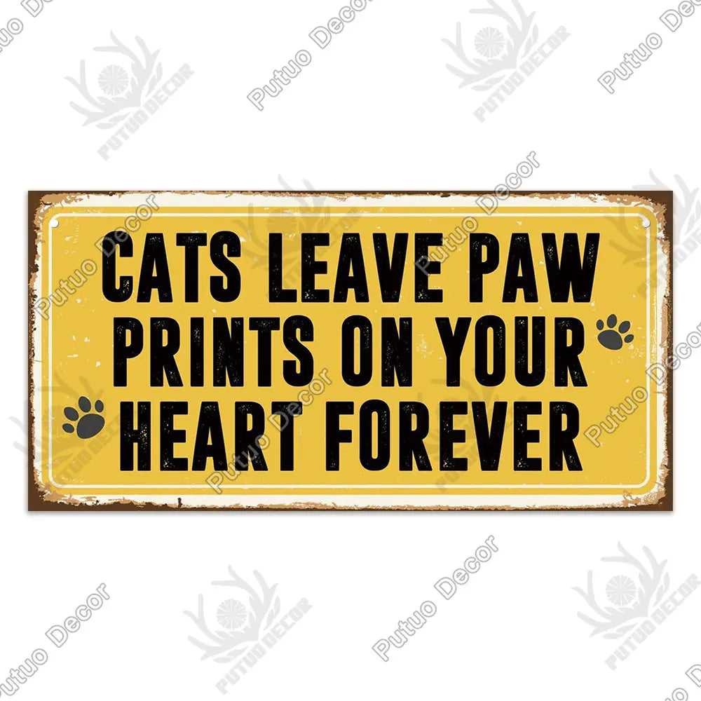 A rustic yellow wooden sign with black text that reads Cats leave paw prints on your heart forever.