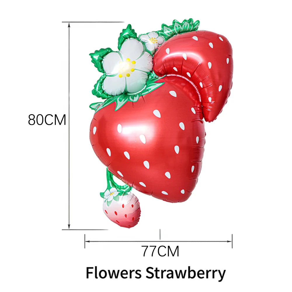 A red strawberry shaped balloon decoration with green leaves and white flowers.