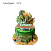 A cake topper featuring a green dinosaur figure with an open mouth and a bright yellow sun, placed on a decorative cake stand