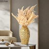 Golden wrinkle ceramic tabletop vase filled with dried grasses and botanicals