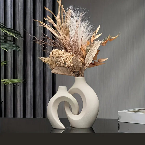 A modern Nordic hollow design vase set of two featuring dried grasses and foliage against a gray background.