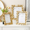 A set of three gold-framed photo frames with leaf borders displayed on a white surface.