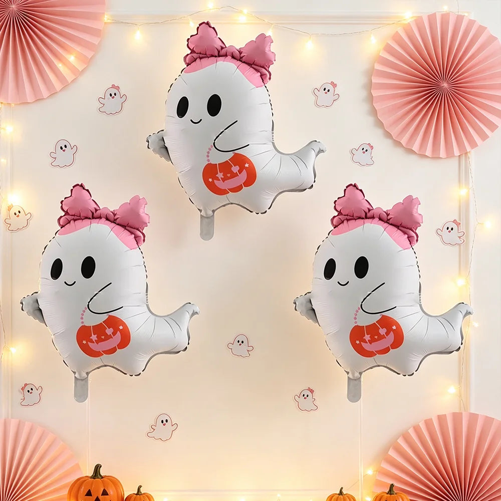 A set of cute pink bow ghost foil balloons used as Halloween party decorations with string lights and orange pumpkins.