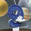 A blue glitter number eight candle decorated with stars and a white planet design.