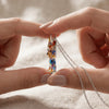 A close-up of a hand holding a Yorkshire Terrier acrylic pendant necklace against a neutral background.