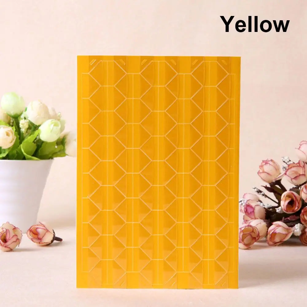 A yellow PVC photo corner protector with a honeycomb pattern displayed next to white flowers.