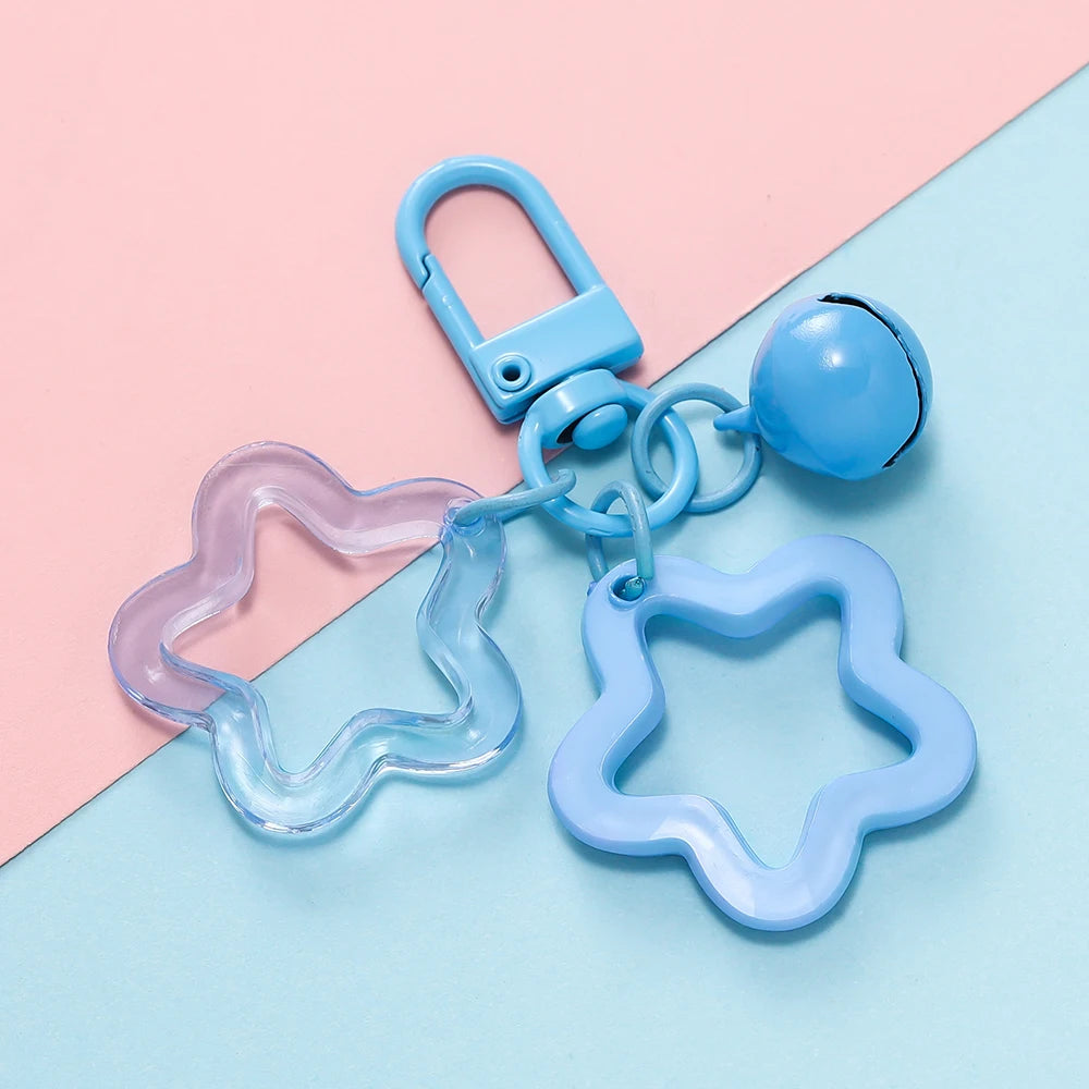 A collection of light blue and purple plastic charms and a keychain with a clasp on a pink and blue background.