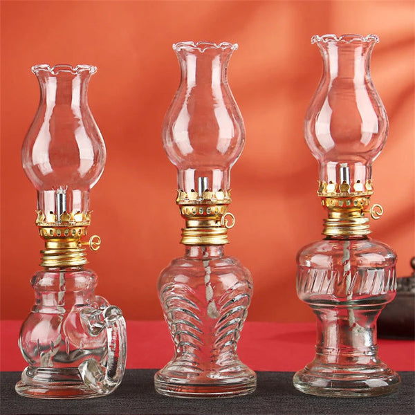 Three vintage glass oil lamps of varying heights and styles displayed on a dark surface.