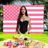 A woman posing in front of a large American flag tapestry with pink and white stripes and stars.
