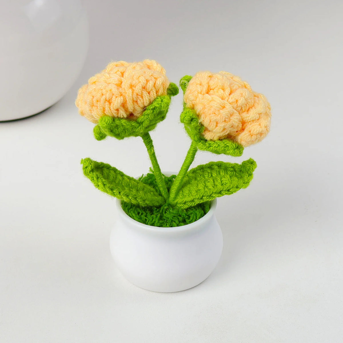 Hand woven crochet orange flowers growing in a green pot