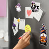 A hand is placing a Halloween fridge magnet set onto a dark refrigerator, featuring trick-or-treat themed designs.