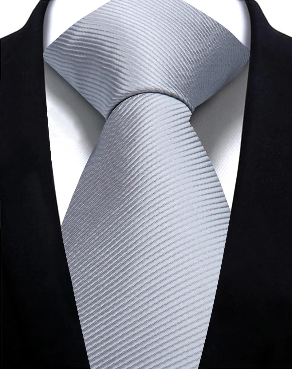 A close-up of a silver striped silk necktie worn under a black suit jacket.