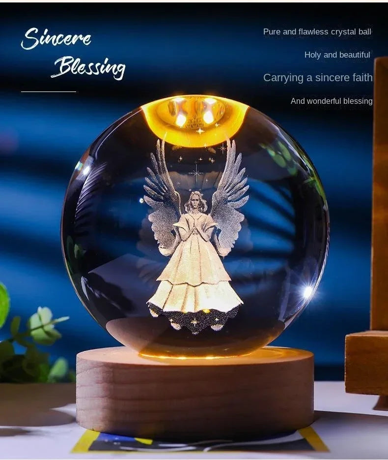 A clear glass crystal ball night light featuring a silhouette of an angel with wings glowing inside.