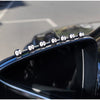 Gros plan sur le pare-chocs d'une voiture noire décoré de petits ornements en forme d'elfes ronds.