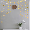 A decorative garland featuring gold and silver star shapes and polka dots hanging on a gray wall above a clock.