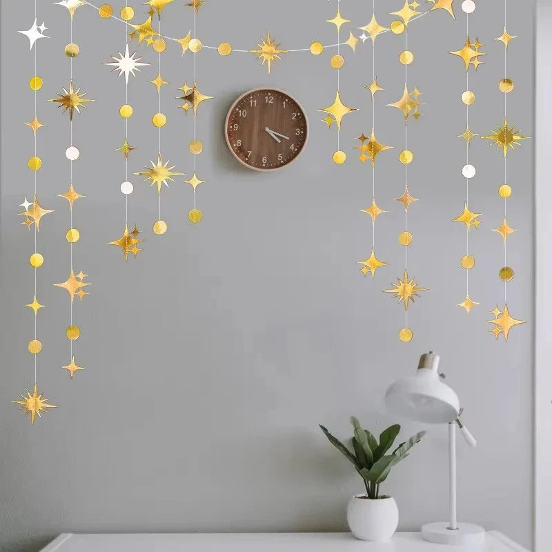 A decorative garland featuring gold and silver star shapes and polka dots hanging on a gray wall above a clock.