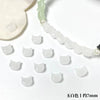 A string of translucent white cat head glass beads for jewelry making, with a larger bead visible in the background.