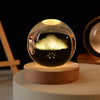 A glass crystal ball night light with a warm glow sits on a round wooden base.
