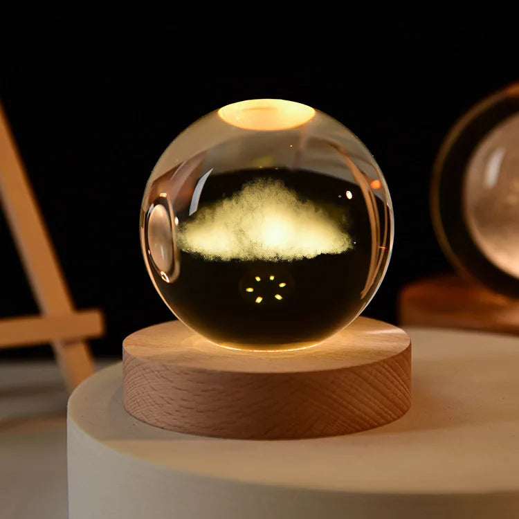 A glass crystal ball night light with a warm glow sits on a round wooden base.