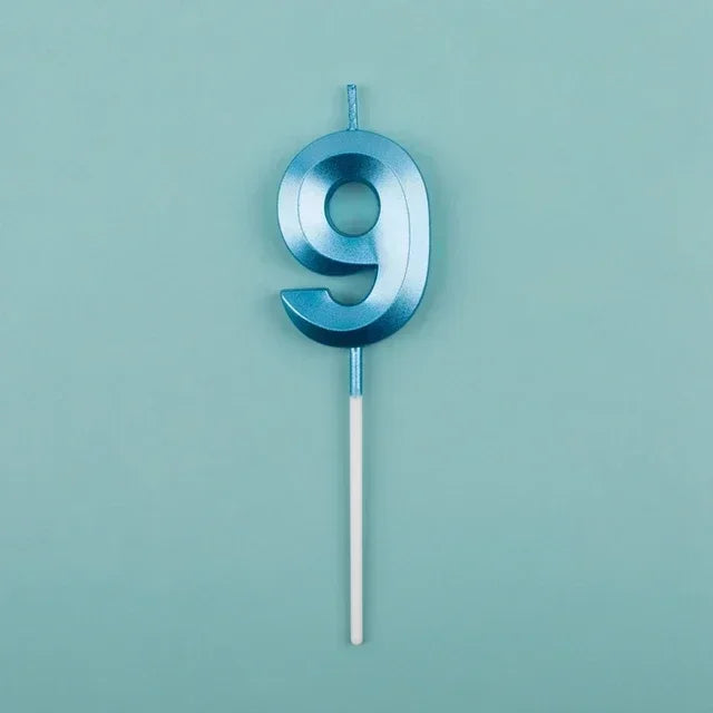 A blue number nine candle with a pink wick against a light teal background.