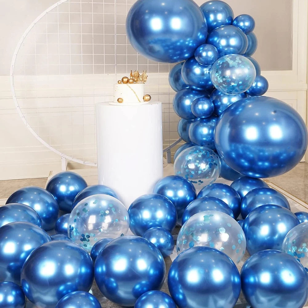 A display of metallic blue and silver balloons arranged in a vertical cluster with a white cake on a pedestal.
