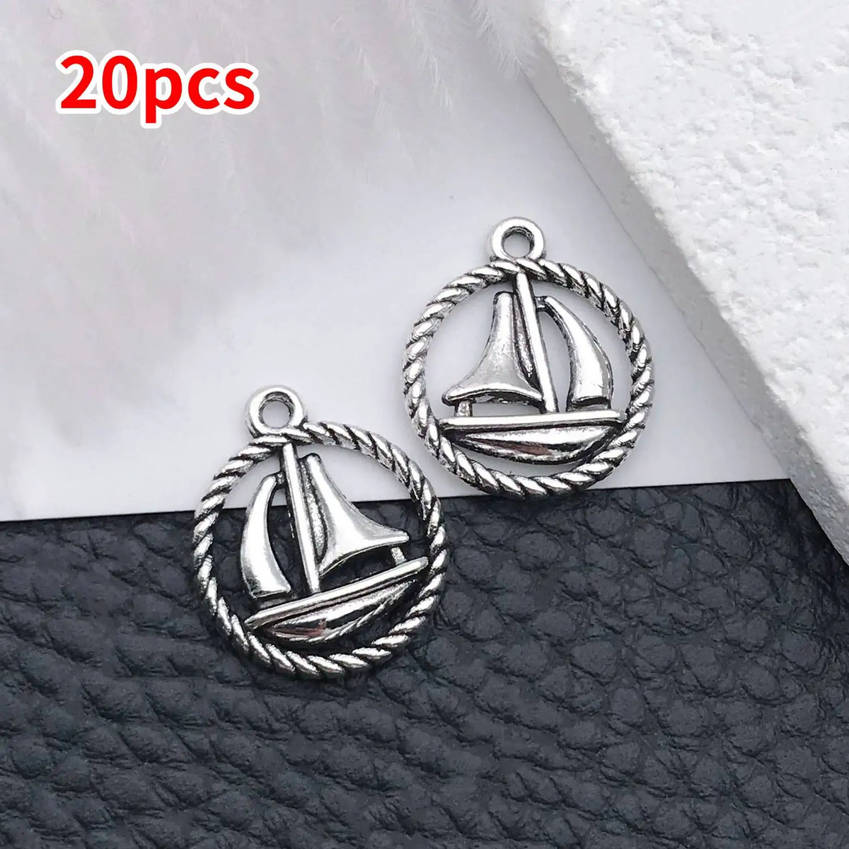 20 pieces of silver vintage ship anchor charms for jewelry making displayed on a dark surface.