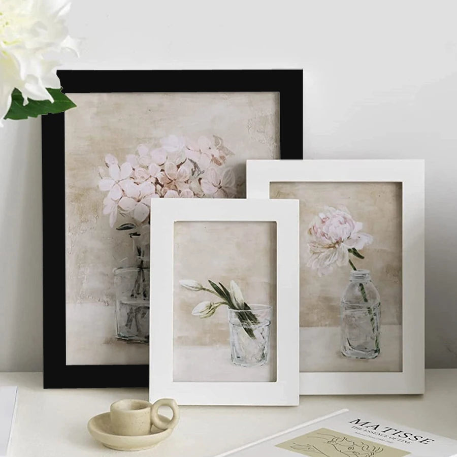 A collection of framed botanical prints featuring pink flowers and greenery displayed on a white surface.