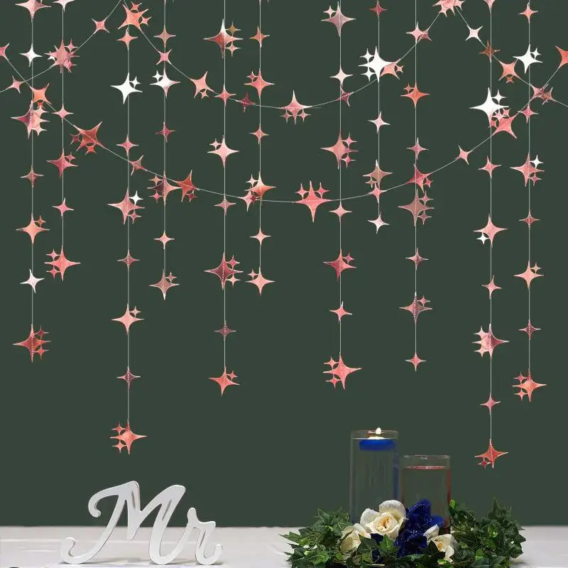 A dark green wall decorated with a shimmering pink and silver star garland hanging down.