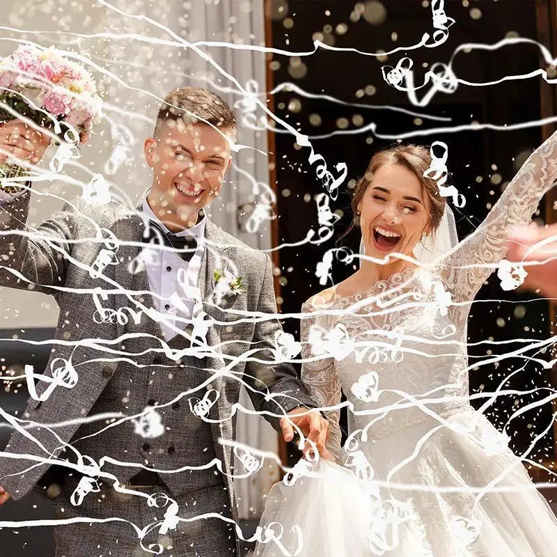Eine glückliche Braut und Bräutigam werden mit weißen Konfetti-Strängen bei ihrer Hochzeit überschüttet.
