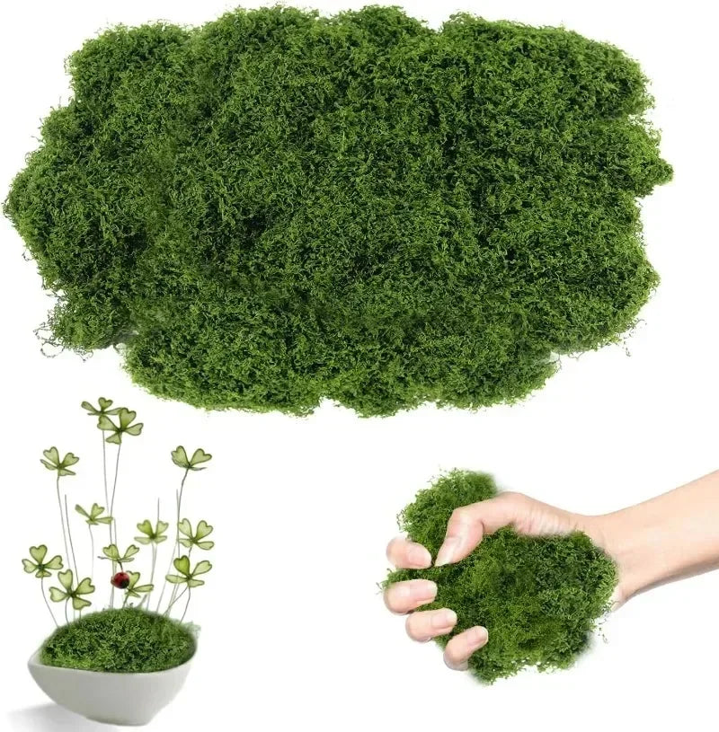 A hand holds a clump of bright green artificial moss, with a large mass of similar moss visible above.