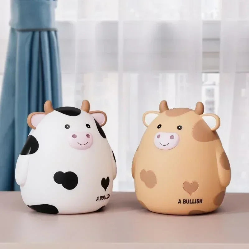 A cartoon cow piggy bank coin holder in white and brown colors sitting on a light surface.