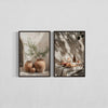 Two framed botanical paintings featuring olive branches and natural light, displayed on a white wall.