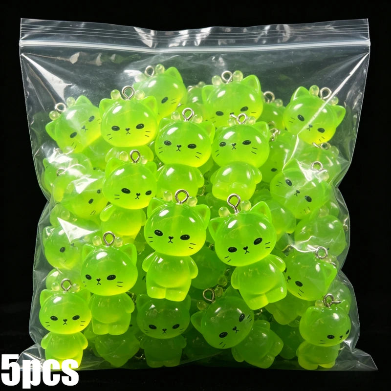 A bag filled with glow-in-the-dark resin charms shaped like cats and ducks in various shades of lime green.