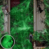 Green glow-in-the-dark spider web Halloween decor with fake spiders on a door.