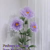 A bouquet of three purple silk poppy flower heads on green stems displayed in a circular base.