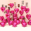 A display of pink and magenta heart foil balloons arranged against a light pink wall.