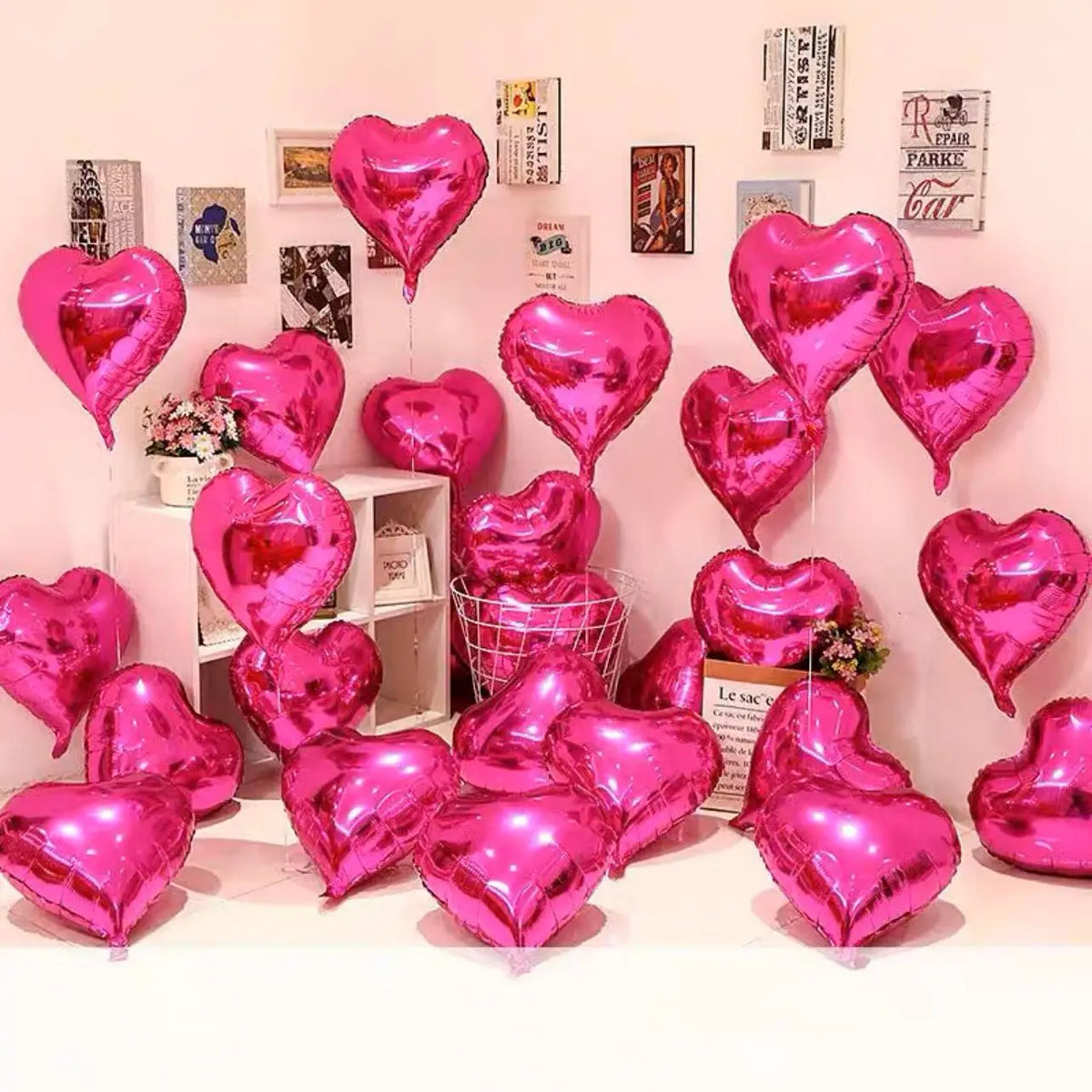 A display of pink and magenta heart foil balloons arranged against a light pink wall.