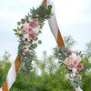 A floral arch decorated with dusty rose and white roses and green eucalyptus leaves for a wedding.