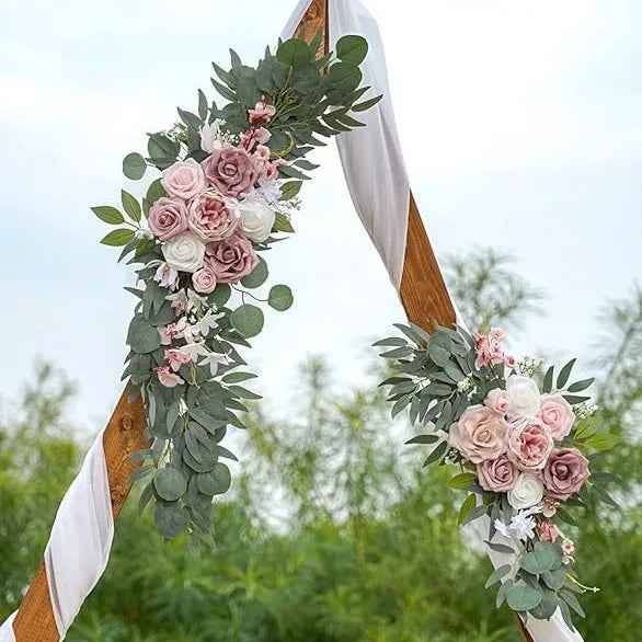 A floral arch decorated with dusty rose and white roses and green eucalyptus leaves for a wedding.