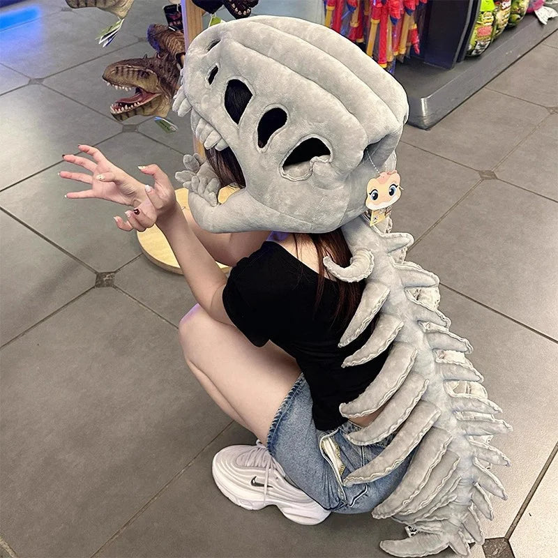 A person wearing a gray dinosaur skeleton costume with a head and spine, sitting on the floor.