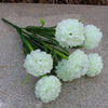 Un bouquet de fleurs d'hydrangea blanches artificielles posé sur une surface de pierre grise.