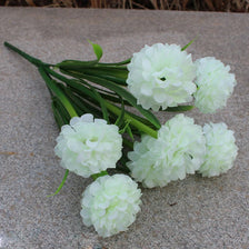 A bouquet of artificial white hydrangea flowers lying on a gray stone surface.