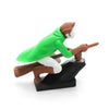 A figurine of a witch and wizard figure with brown hair and green clothing is shown on a dashboard drift decor.